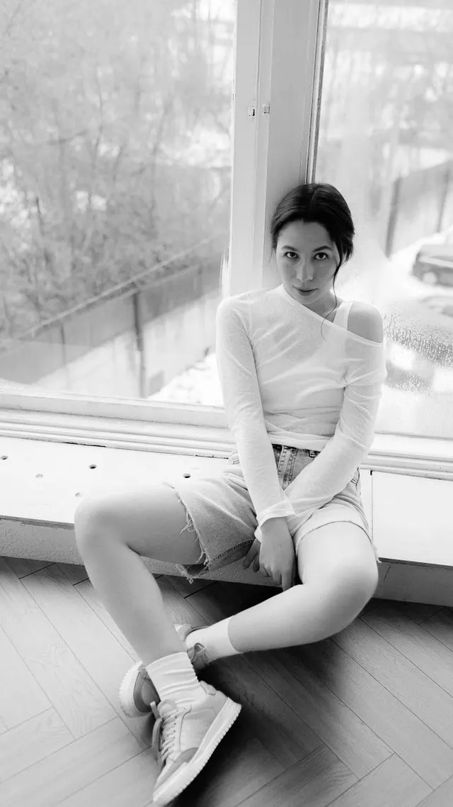 Woman seated by a window in a black-and-white portrait